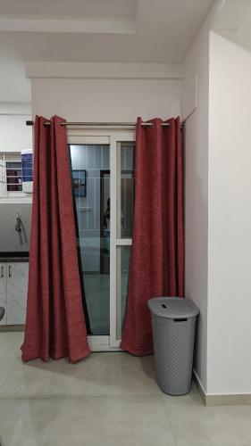 a kitchen with red curtains and a trash can at 116 Home Tales by Tipiverse, BTM Layout - NO CAR PARKING in Bengaluru