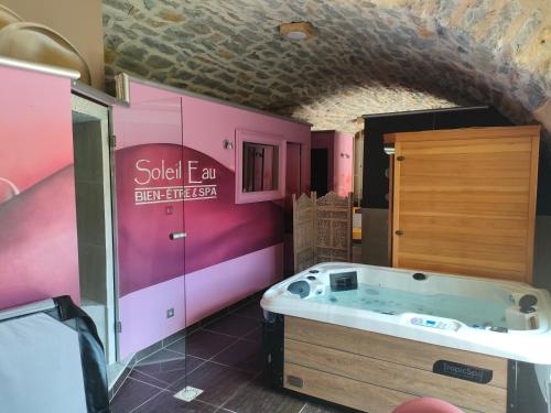 - une salle de bains pourvue d'un bain à remous dans une chambre rose dans l'établissement lesoleilo, à Mostuéjouls