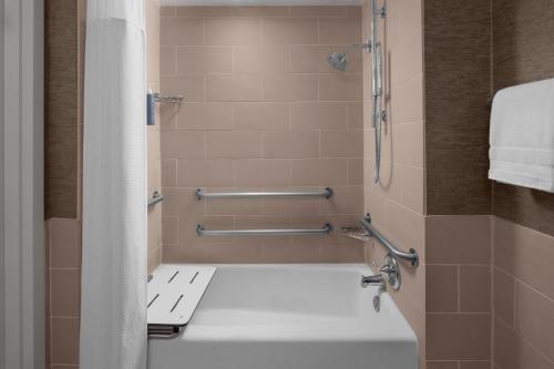 a bathroom with a shower with a white tub at The Westin Dallas Fort Worth Airport in Irving