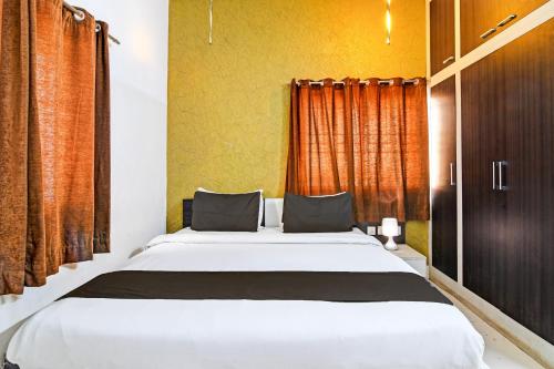 a bedroom with a large bed with orange curtains at Hotel O Home Bm-x in Khandagiri