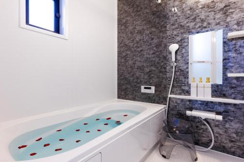 a white bath tub in a bathroom with a tile wall at オープンセール 2棟貸切 最大20名ビーチまで車で4分 駐車場4台 tla&tdy ツインズロッジA棟B棟貸切 in Yomitan