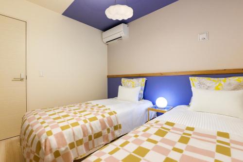 two beds in a small room with blue ceilings at オープンセール 2棟貸切 最大20名ビーチまで車で4分 駐車場4台 tla&tdy ツインズロッジA棟B棟貸切 in Yomitan