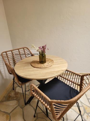 une table en bois avec deux chaises et un vase avec des fleurs dans l'établissement Eternite08, à Charleville-Mézières