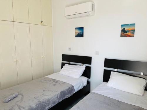 two beds in a room with white walls at Apartments with a luxurious location near the sea in Paphos