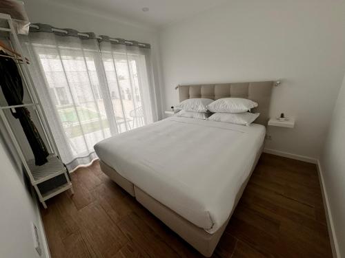 a bedroom with a large bed with white sheets and pillows at D'Felicidade in Caldas da Rainha