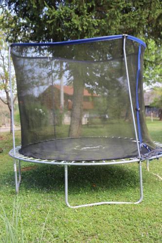 a trampoline with a net on the grass at Wooden house Mali Vrh in Kamanje