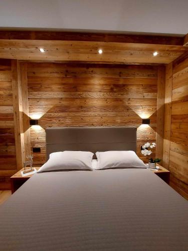 a bedroom with a large bed with wooden walls at Hotel Corona Ferrea in Sappada