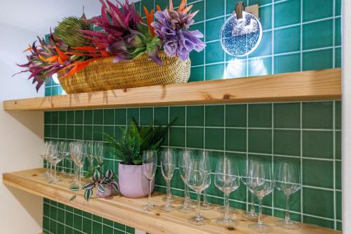 a row of wine glasses on a shelf with flowers at オープンセール 2棟貸切 最大20名ビーチまで車で4分 駐車場4台 tla&tdy ツインズロッジA棟B棟貸切 in Yomitan
