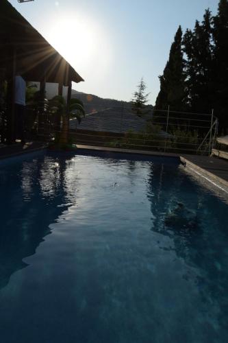 a pool of blue water with the sun in the background at Pacithea Villas in Miléai