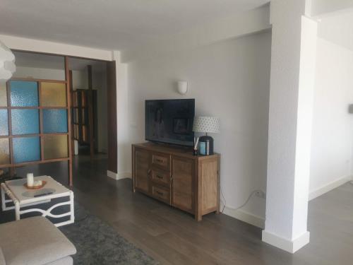 ein Wohnzimmer mit einem Fernseher auf einem Holzschrank in der Unterkunft APARTAMENTO SOL Y MAR Primera Linea in Playa de Gandia