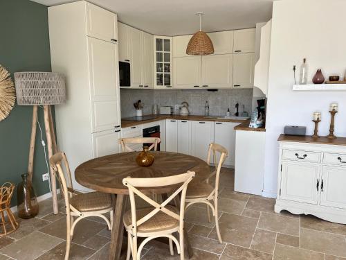 une cuisine avec une table et des chaises en bois dans l'établissement Superbe appartement lumineux en rez de jardin, à Saint-Laurent-du-Var