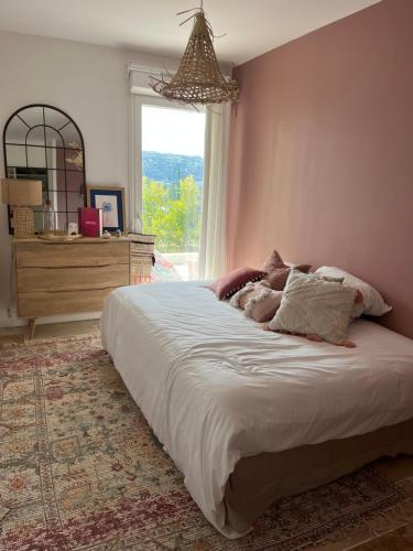 un grand lit dans une chambre avec une fenêtre dans l'établissement Superbe appartement lumineux en rez de jardin, à Saint-Laurent-du-Var