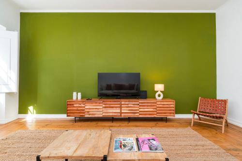 a living room with a television on a green wall at CICIOSO flats João de Deus 2 in Évora