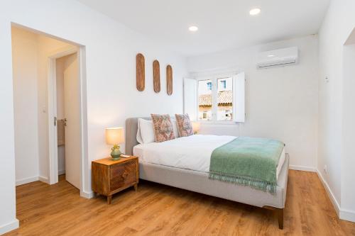 a bedroom with a bed and a table with a lamp at CICIOSO flats João de Deus 2 in Évora