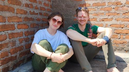 two young women sitting next to a brick wall at Maji Homestay Khajuraho in Khajurāho