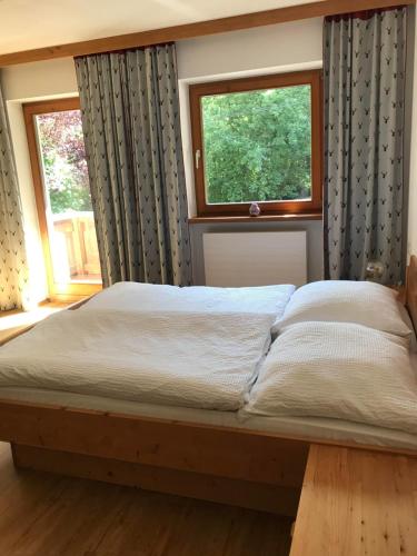 a bed in a bedroom with two windows at Appartement Ginzling Haus Eder in Ginzling