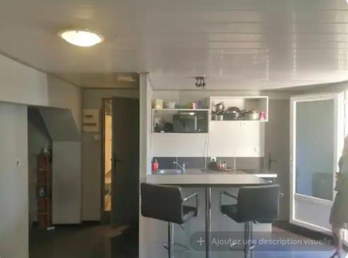 une cuisine avec des placards blancs, un comptoir et des chaises dans l'établissement Appartement proche du stade 1, à Marseille