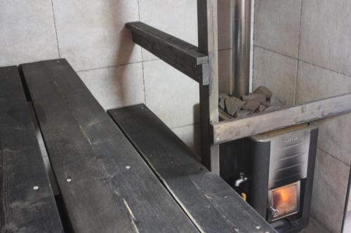 a woodburning stove in a room with a stair case at Koivurannan lomamökit Kotkanpesä in Mikkeli