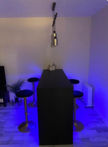 Cette chambre dispose d'un comptoir noir et de tabourets avec des lumières violettes. dans l'établissement Appartement 85m2 La Défense,Balcony, à Courbevoie