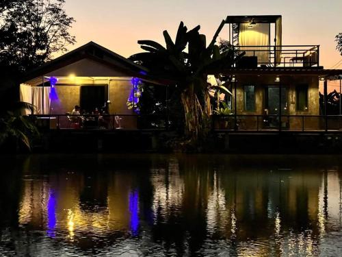 a house sitting on top of a body of water at ฟาร์มสเตย์สุโขทัยบ้านไร่เบสแคมป์ in Ban Wang Luk