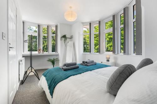 a white bedroom with a large bed with windows at 4BR 3 bath Spacious apartment, Sleeps upto 8 free parking in Allesley