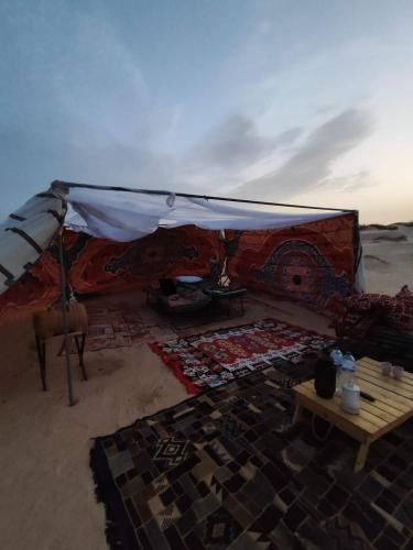 a tent in the desert with a table and a rug at Private Camp25km-from DOUZ in Douz