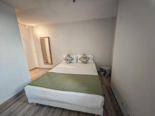 - une chambre avec un lit blanc et une couverture verte dans l'établissement Appartement T2 les Capucines, à La Ciotat