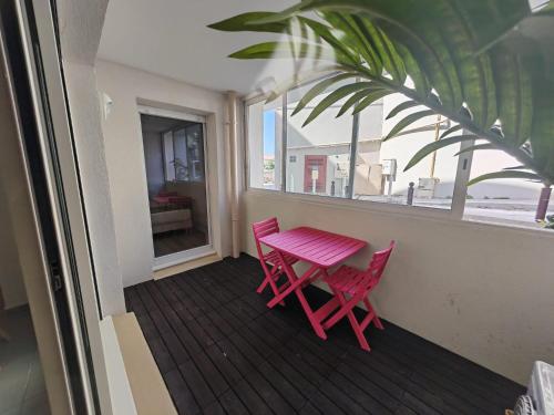 une table rose et deux chaises sur un balcon dans l'établissement Appartement T2 les Capucines, à La Ciotat