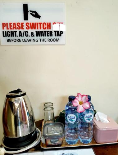 a counter top with water bottles and a tea kettle at Kaia Lovina Guest House Junior Suite in Lovina