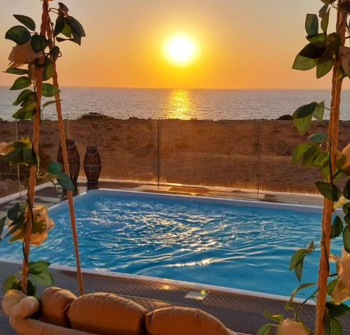 a swimming pool with the sunset in the background at Tramonto Luxury Villa No1- Breathtaking sunset view in Karpathos Town