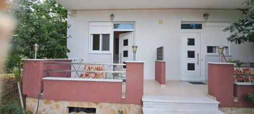 a white house with a red and white front porch at Tranquil new apartmen7t in inland Lefkada in Spanokhórion