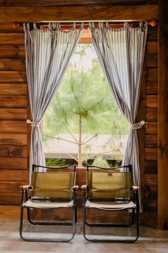 two chairs sitting in front of a window at Dancasa Horse Farm & Homestay in Buôn Chiêt
