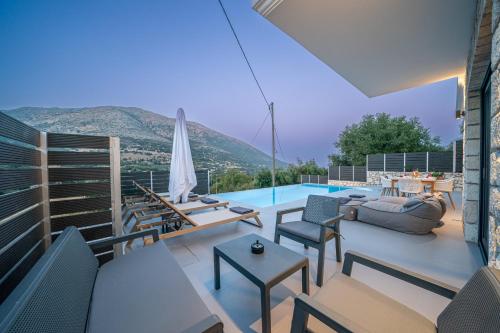 a patio with furniture and a swimming pool with a view at Brand New Stone Villa Aris !! in Divarata