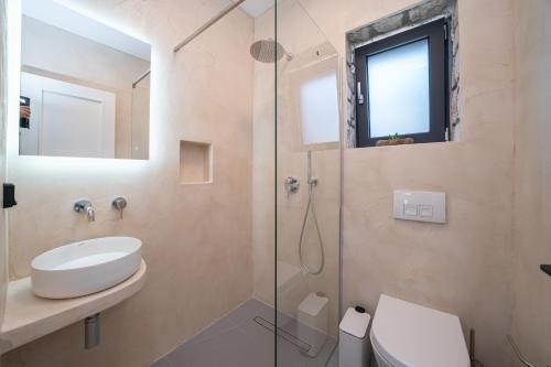 a bathroom with a sink and a glass shower at Brand New Stone Villa Aris !! in Divarata
