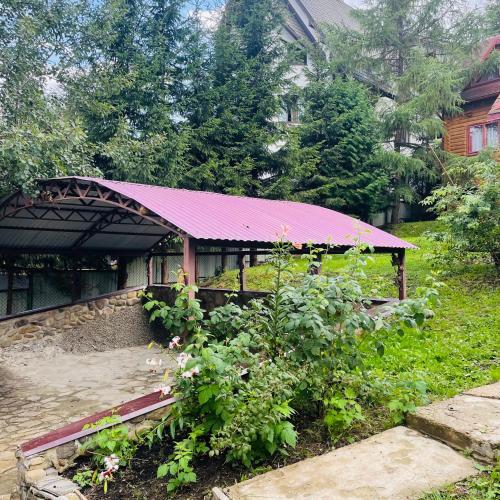 a building with a purple roof and a garden at Еко котедж Яблуницька троянда in Yablunytsya
