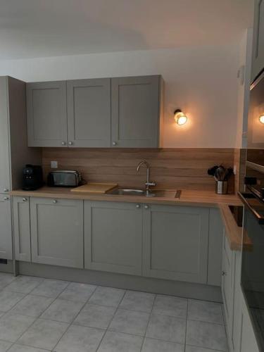 une cuisine avec des armoires blanches et un évier dans l'établissement Gîte du Parc, à Barneville-Carteret