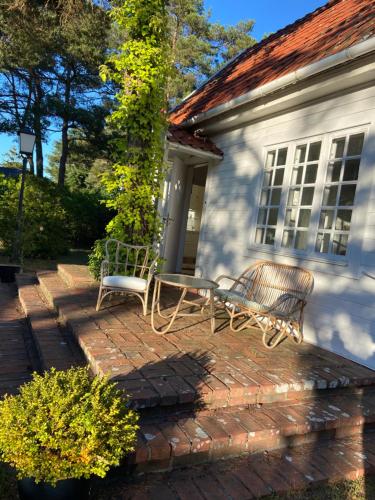 a house with two chairs on a brick patio at Summer house close to the beach with 12 beds in Höllviken