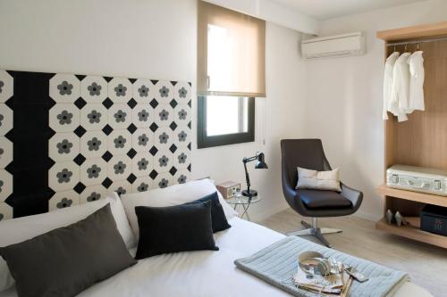 um quarto com uma cama branca e uma cadeira preta em Eric Vökel Boutique Apartments - Sagrada Familia Suites em Barcelona