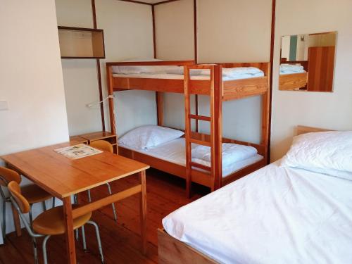 a room with bunk beds and a table and a desk at Chata Borůvka u Máchova jezera - free PADDLEBOARD in Doksy