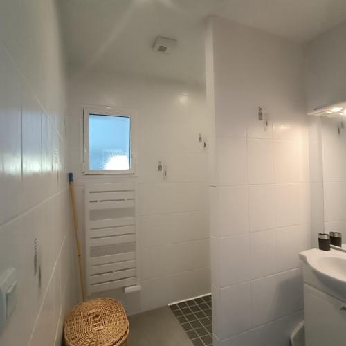 une salle de bain blanche avec un lavabo et une douche dans l'établissement Maison proche de la mer, à Plestin-les-Grèves