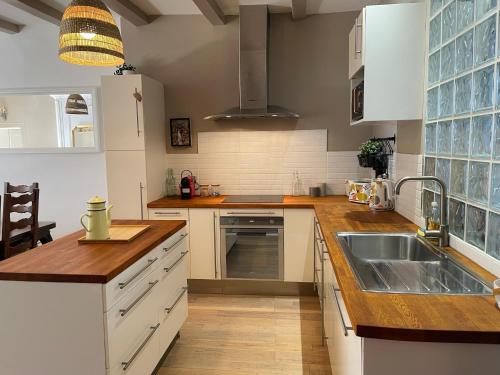 une cuisine avec des armoires blanches et un évier dans l'établissement Maison Gabriel - Logement charmant au cœur de la Cité Médiévale - T3 75m2, à Albertville