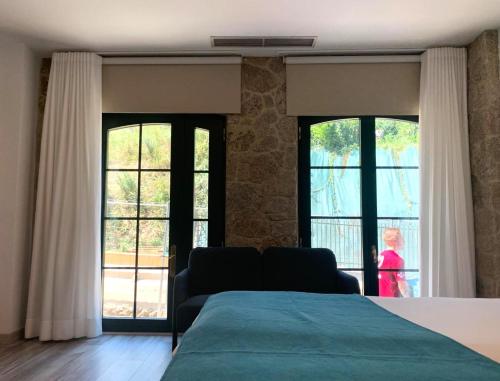 a bedroom with a bed and two large windows at Hotel Pombal Rooms in Santiago de Compostela