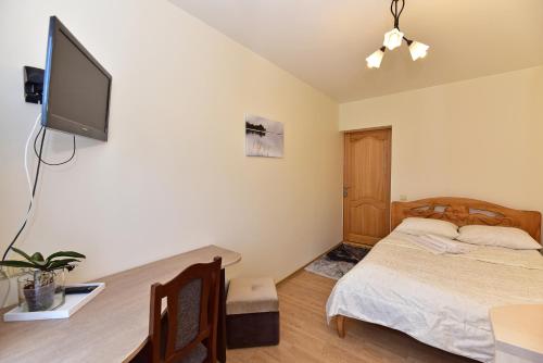 Un dormitorio con una cama y un televisor de pantalla plana. en Vilaverona, en Palanga