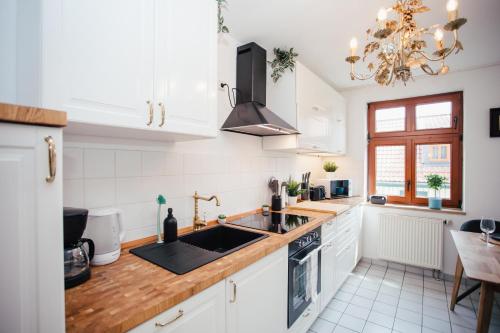 a kitchen with white cabinets and a sink at Exklusive Goethe-Suite am Brocken by Meis in Wernigerode Zentral in Wernigerode