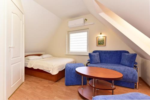ein Zimmer mit einem Bett, einer blauen Couch und einem Tisch in der Unterkunft Vilaverona in Palanga