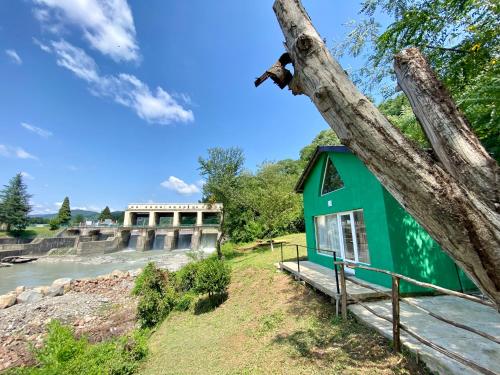 una casa verde al lado de un árbol al lado de un río en Green house, en Kutaisi
