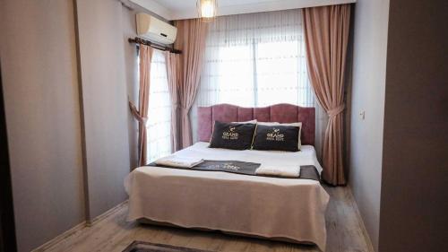 a bed with two pillows in front of a window at New Armila Suites in Trabzon