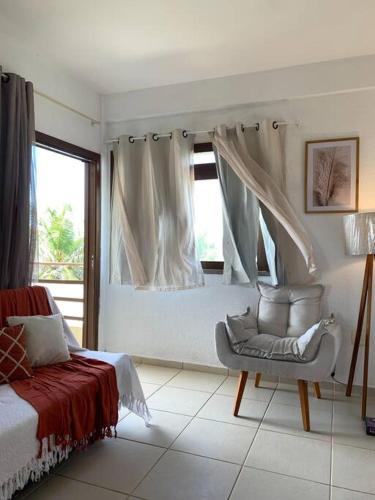 a bedroom with a bed and a chair and a window at Flat Marezzi - Pé na areia - Taíba CE in São Gonçalo do Amarante