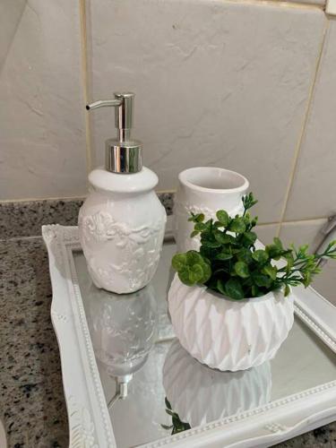two white vases and a plant on a glass table at Flat Marezzi - Pé na areia - Taíba CE in São Gonçalo do Amarante