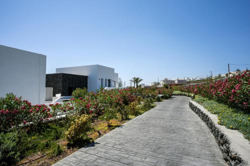 a cobblestone path through a garden of flowers at Cresanto Luxury Suites in Imerovigli